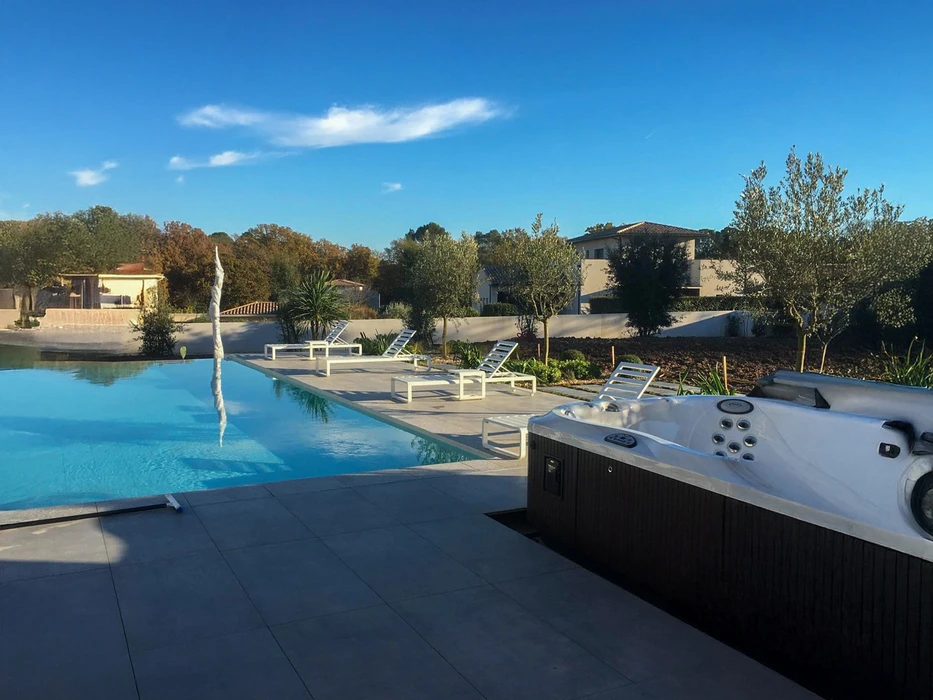 Piscine extérieure avec escalier intégré en courbe, entourée de margelles en pierre naturelle et carrelage terre cuite