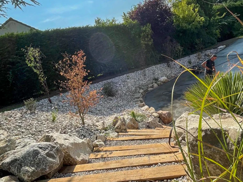 Piscine extérieure rectangulaire avec margelle blanche et plage en bois, située dans jardin paysager avec gazon
